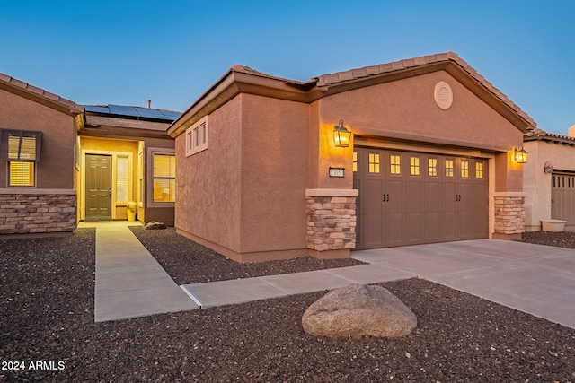 view of front facade featuring a garage and solar panels