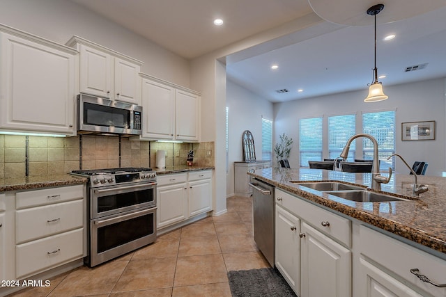 kitchen featuring dark stone counters, appliances with stainless steel finishes, sink, and white cabinets