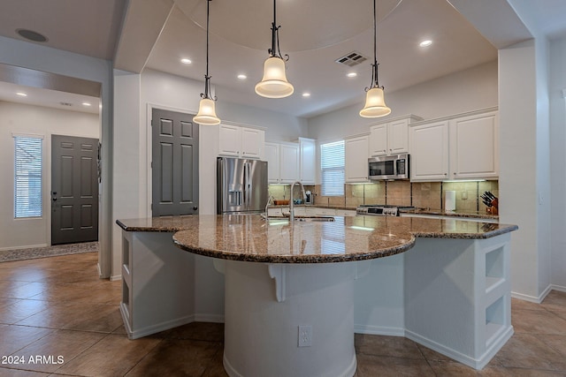 kitchen with a large island, stainless steel appliances, hanging light fixtures, and white cabinets