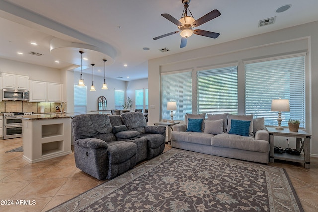 living room with a wealth of natural light, sink, light tile patterned floors, and ceiling fan