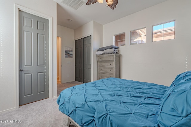 bedroom featuring a closet, light colored carpet, and ceiling fan