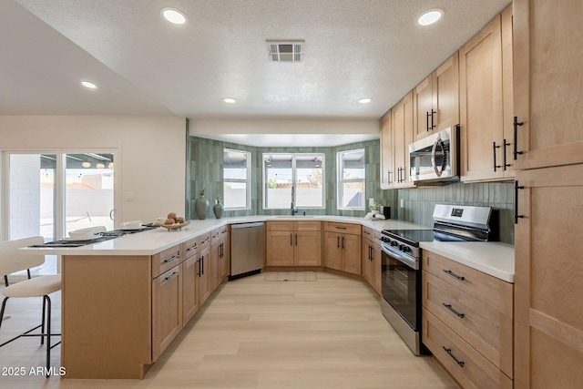1609 W Yukon Dr, Phoenix, AZ 85027 - kitchen featuring appliances with stainless steel finishes, light brown cabinets, a peninsula, healthy amount of natural light, and recessed lighting