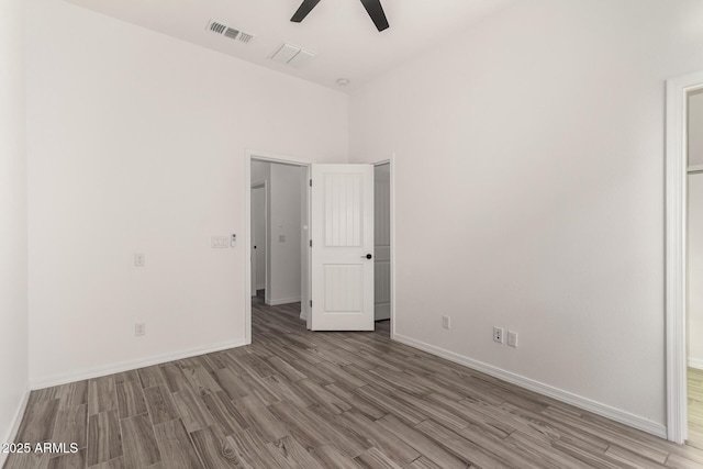 spare room with a high ceiling, ceiling fan, and light hardwood / wood-style floors