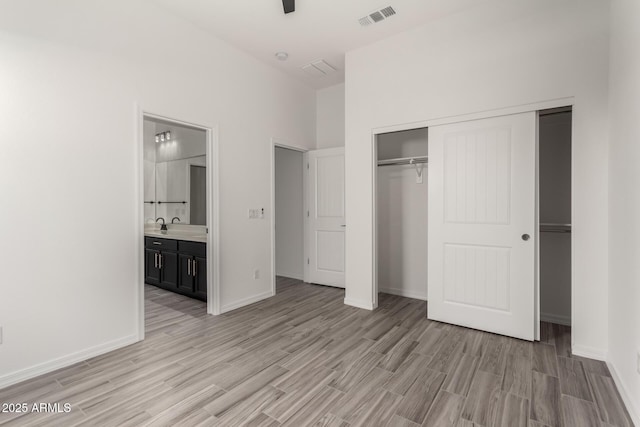 unfurnished bedroom with connected bathroom, light hardwood / wood-style floors, and a closet