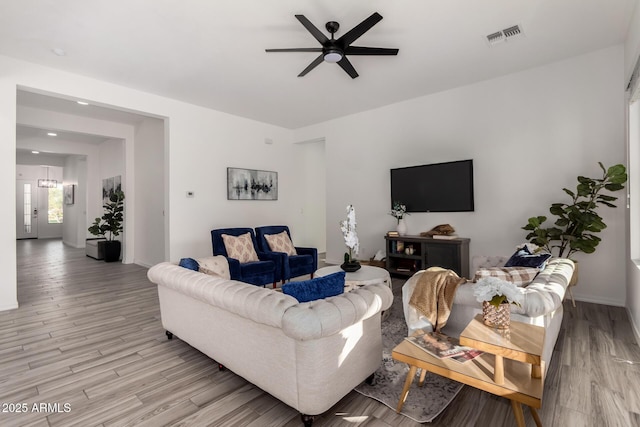 living room with ceiling fan with notable chandelier and light hardwood / wood-style flooring