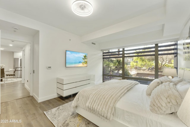 bedroom featuring wood-type flooring and stainless steel refrigerator