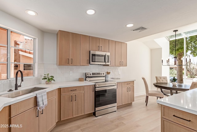 6439 E Redmont Dr, Mesa, AZ 85215 - kitchen with stainless steel appliances, a chandelier, backsplash, light wood-type flooring, and light countertops