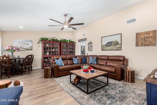 living room featuring ceiling fan, lofted ceiling, and light wood-type flooring