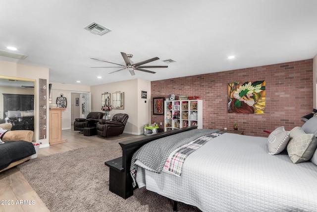 bedroom featuring light hardwood / wood-style floors, ceiling fan, and brick wall