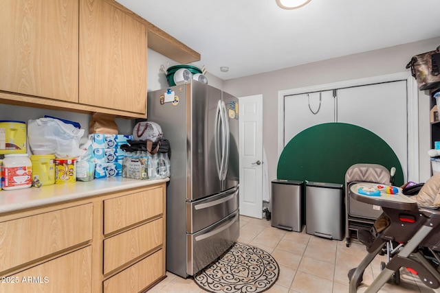 kitchen featuring light brown cabinets, light tile patterned floors, and stainless steel refrigerator