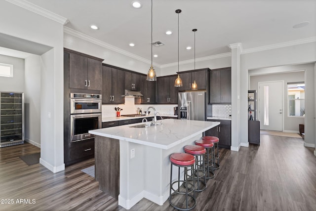 1555 E Ocotillo Rd Unit 16, Phoenix, AZ 85014 - kitchen featuring appliances with stainless steel finishes, beverage cooler, under cabinet range hood, dark brown cabinetry, and recessed lighting