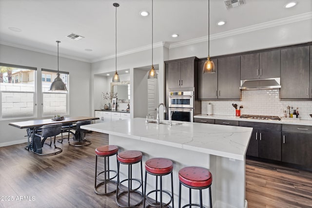 1555 E Ocotillo Rd Unit 16, Phoenix, AZ 85014 - kitchen featuring under cabinet range hood, stainless steel appliances, a breakfast bar, tasteful backsplash, and a sink