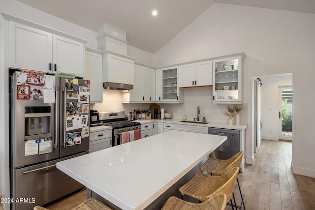 kitchen featuring stainless steel appliances, white cabinetry, sink, and a kitchen bar