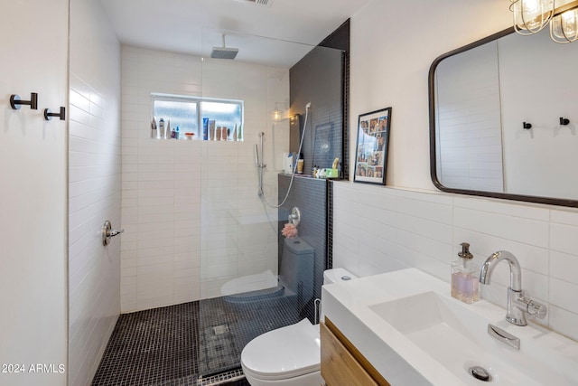 bathroom featuring vanity, toilet, tile walls, and a tile shower