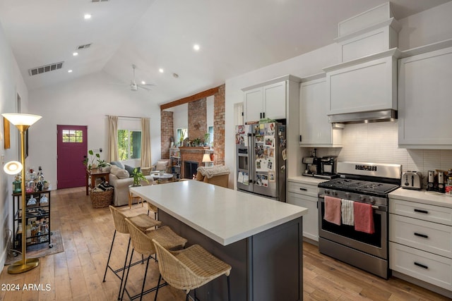 kitchen with a breakfast bar area, white cabinetry, a center island, appliances with stainless steel finishes, and a fireplace