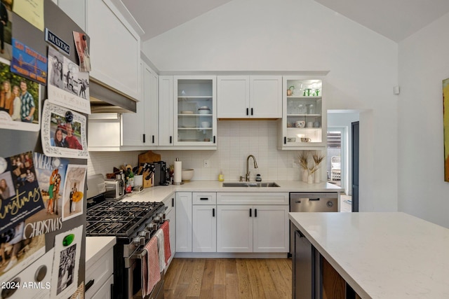 kitchen featuring lofted ceiling, sink, stainless steel appliances, and white cabinets