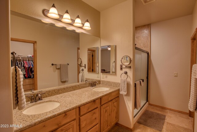 bathroom featuring double vanity, a shower stall, and a sink