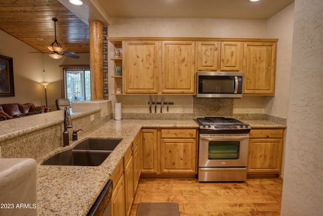 kitchen featuring light wood finished floors, appliances with stainless steel finishes, light stone counters, light brown cabinets, and a sink