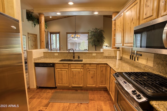 kitchen with vaulted ceiling with beams, stainless steel appliances, a sink, wood finished floors, and a peninsula