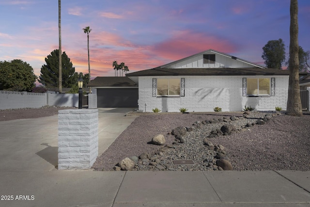 ranch-style home featuring an outbuilding, brick siding, an attached garage, fence, and driveway