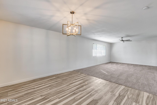 empty room with an inviting chandelier, baseboards, and wood finished floors