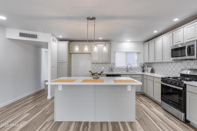 kitchen featuring light wood-type flooring, a kitchen island, visible vents, and stainless steel appliances