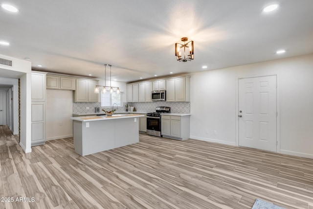 kitchen featuring backsplash, appliances with stainless steel finishes, light countertops, and a notable chandelier