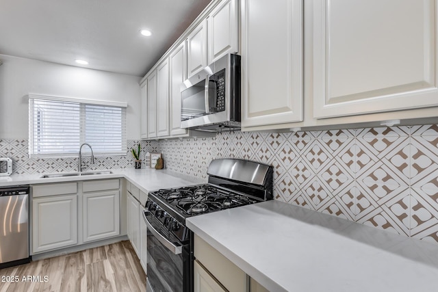 kitchen featuring decorative backsplash, stainless steel appliances, light countertops, white cabinetry, and a sink