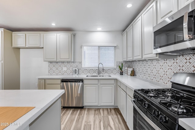 kitchen with stainless steel appliances, a sink, and light countertops