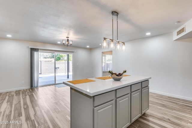 kitchen featuring light wood finished floors, gray cabinets, light countertops, visible vents, and a kitchen island