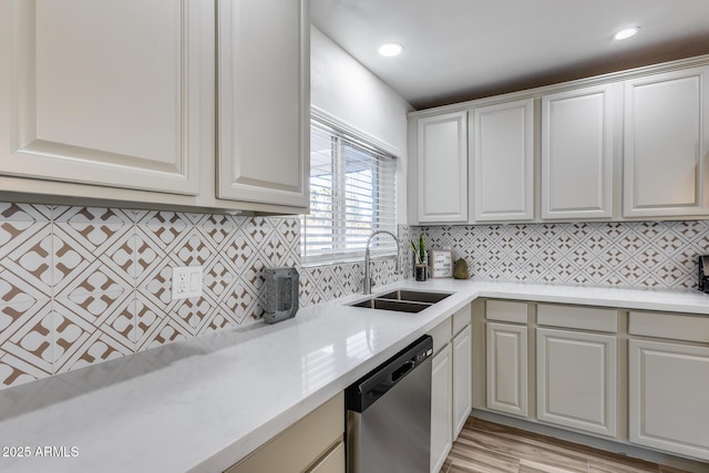 kitchen with dishwasher, tasteful backsplash, light wood finished floors, and a sink