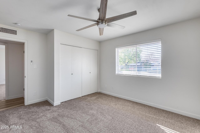 unfurnished bedroom with ceiling fan, visible vents, baseboards, a closet, and carpet