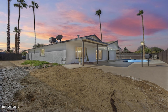 rear view of property featuring concrete driveway, a fenced backyard, a patio, and brick siding