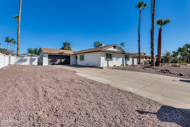 single story home with a garage, concrete driveway, brick siding, and fence