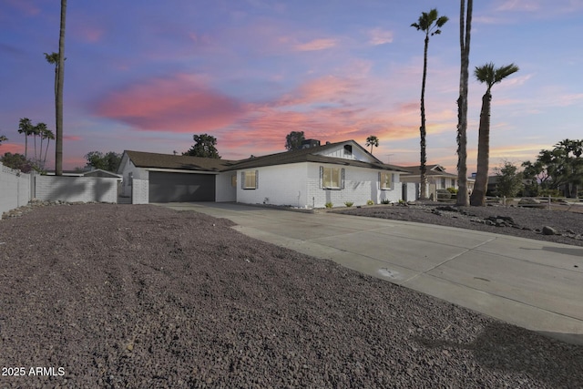 ranch-style house featuring concrete driveway, brick siding, an attached garage, and fence