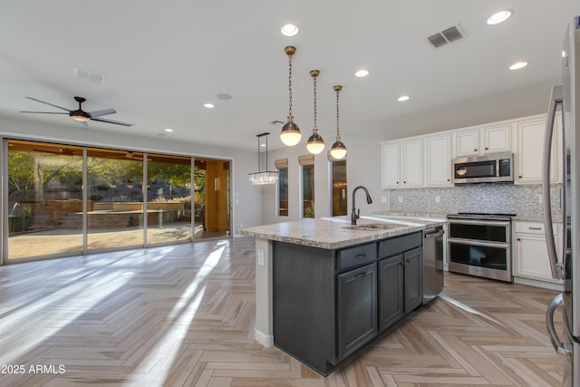 3285 Maverick Dr, Wickenburg, AZ 85390 - kitchen featuring appliances with stainless steel finishes, a sink, white cabinets, an island with sink, and backsplash