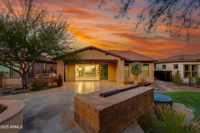 3285 Maverick Dr, Wickenburg, AZ 85390 - back of property at dusk featuring stucco siding, a tile roof, a patio area, and an outdoor kitchen