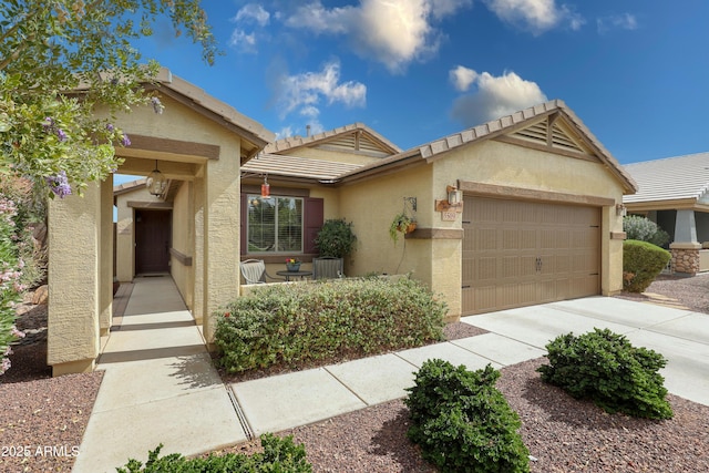 view of front of house with a tile roof, driveway, an attached garage, and stucco siding