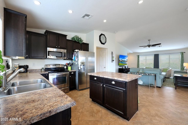 kitchen featuring a sink, visible vents, vaulted ceiling, appliances with stainless steel finishes, and a center island