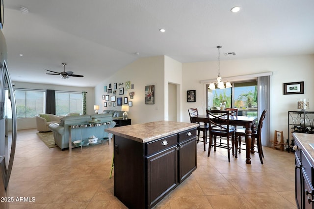 kitchen with lofted ceiling, plenty of natural light, visible vents, and ceiling fan with notable chandelier