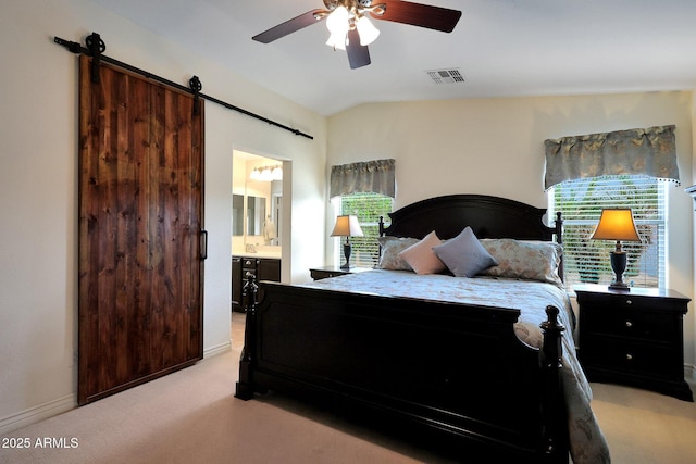 bedroom featuring lofted ceiling, visible vents, ensuite bathroom, a barn door, and light carpet