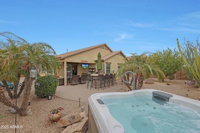 back of property featuring a hot tub, fence, outdoor dining area, a patio area, and stucco siding