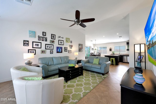 living room featuring ceiling fan, visible vents, vaulted ceiling, and light tile patterned flooring