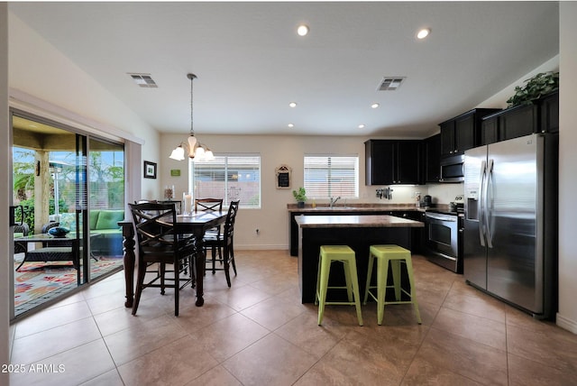 kitchen with a kitchen island, visible vents, stainless steel appliances, and dark cabinets