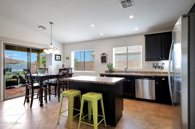 kitchen with visible vents, appliances with stainless steel finishes, a sink, a kitchen island, and dark cabinets