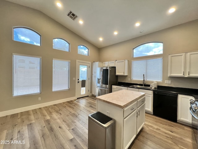 kitchen with white cabinetry, stainless steel fridge, black dishwasher, and sink