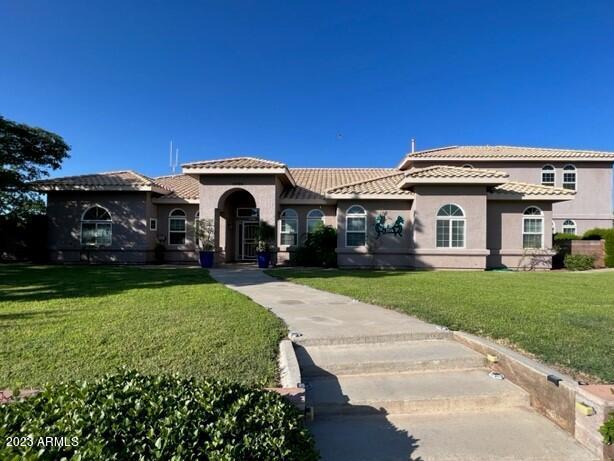 mediterranean / spanish home featuring a front yard, a tiled roof, and stucco siding