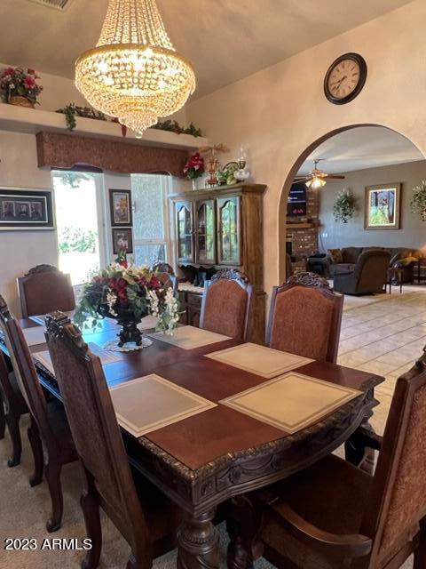 dining space with arched walkways and ceiling fan with notable chandelier