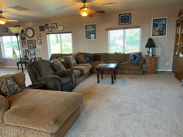 living room featuring ceiling fan, carpet, visible vents, and baseboards