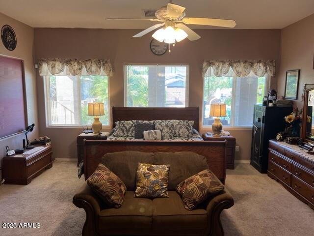 bedroom featuring light carpet, baseboards, and a ceiling fan